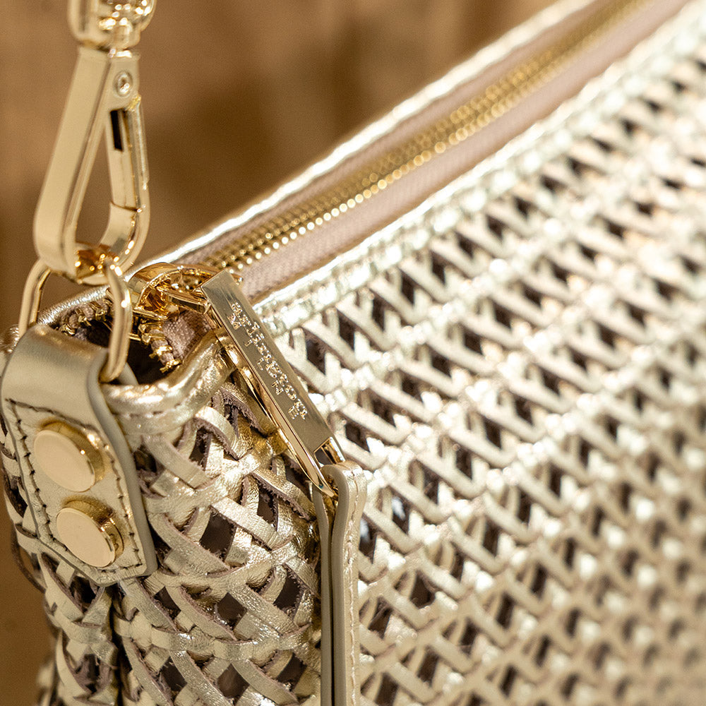 Close-up of an Arlington Milne gold handbag with a weave textured pattern and gold zipper.